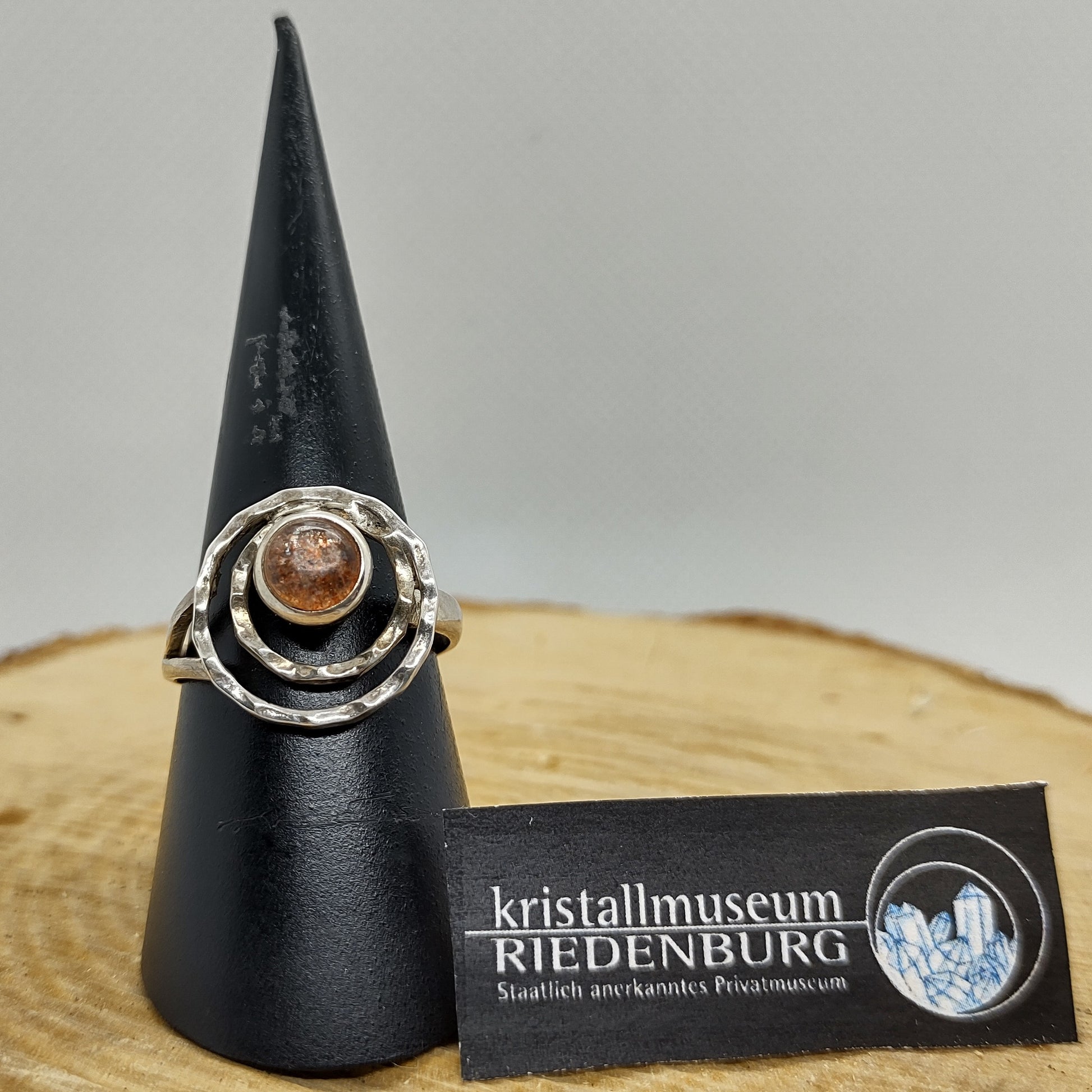 Silberring mit aussergewöhnlicher Spiralfassung, in deren Mitte ein runder, strahlend oranger Sonnenstein-Cabochon sitzt.