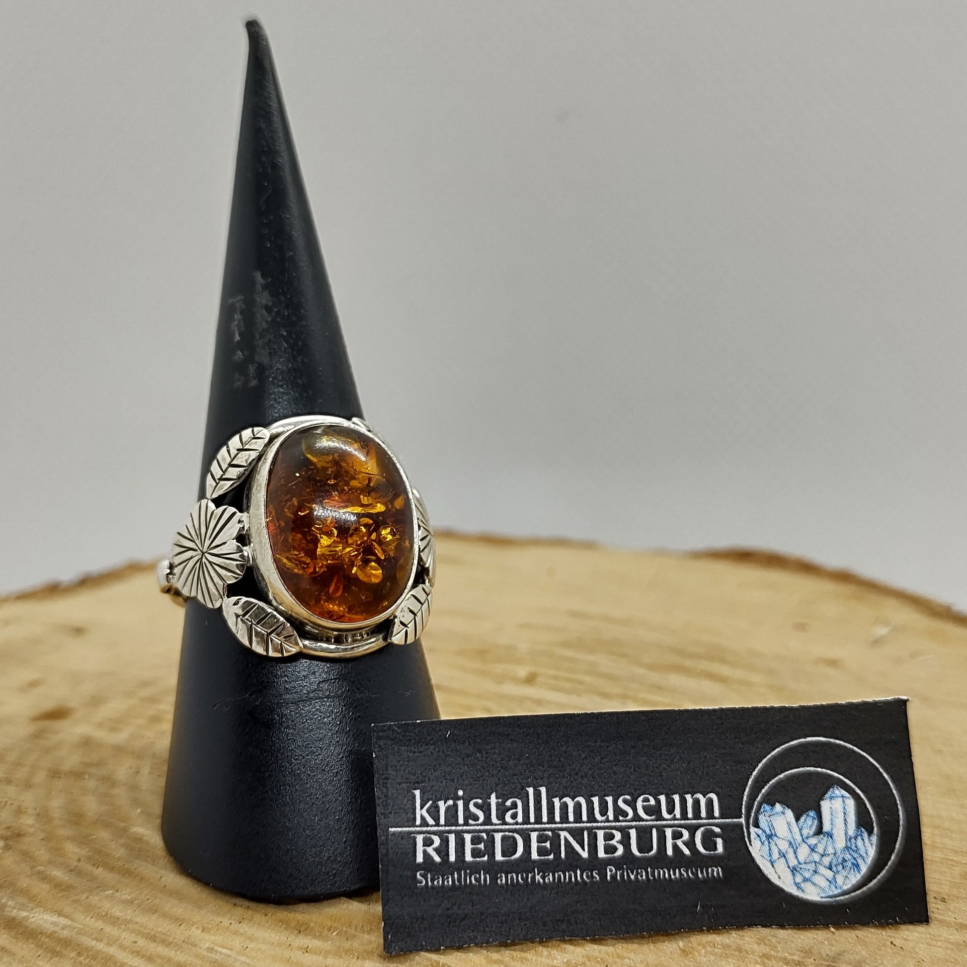 Bernstein-Ring in lebendigem Cognac-Ton. Rechteckiger Cabochon, 1,5cm, in verspielter Silberfassung, Altsilber.